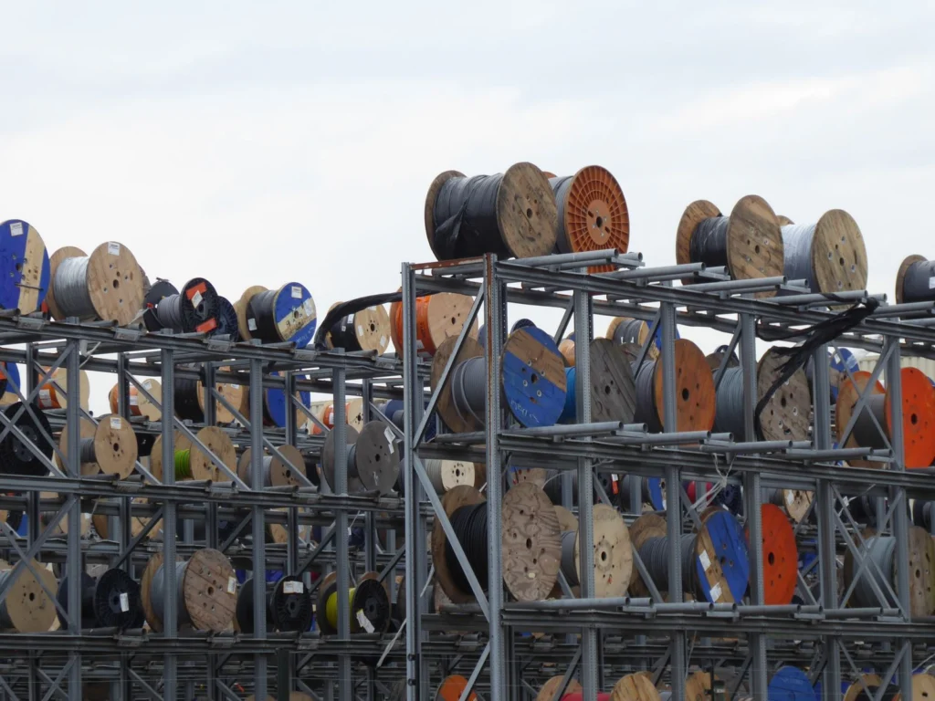 Carretes de cable almacenados en estantería metálica al aire libre