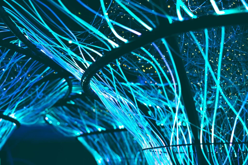 Hilos de fibra óptica iluminados en tonos azules sobre fondo oscuro