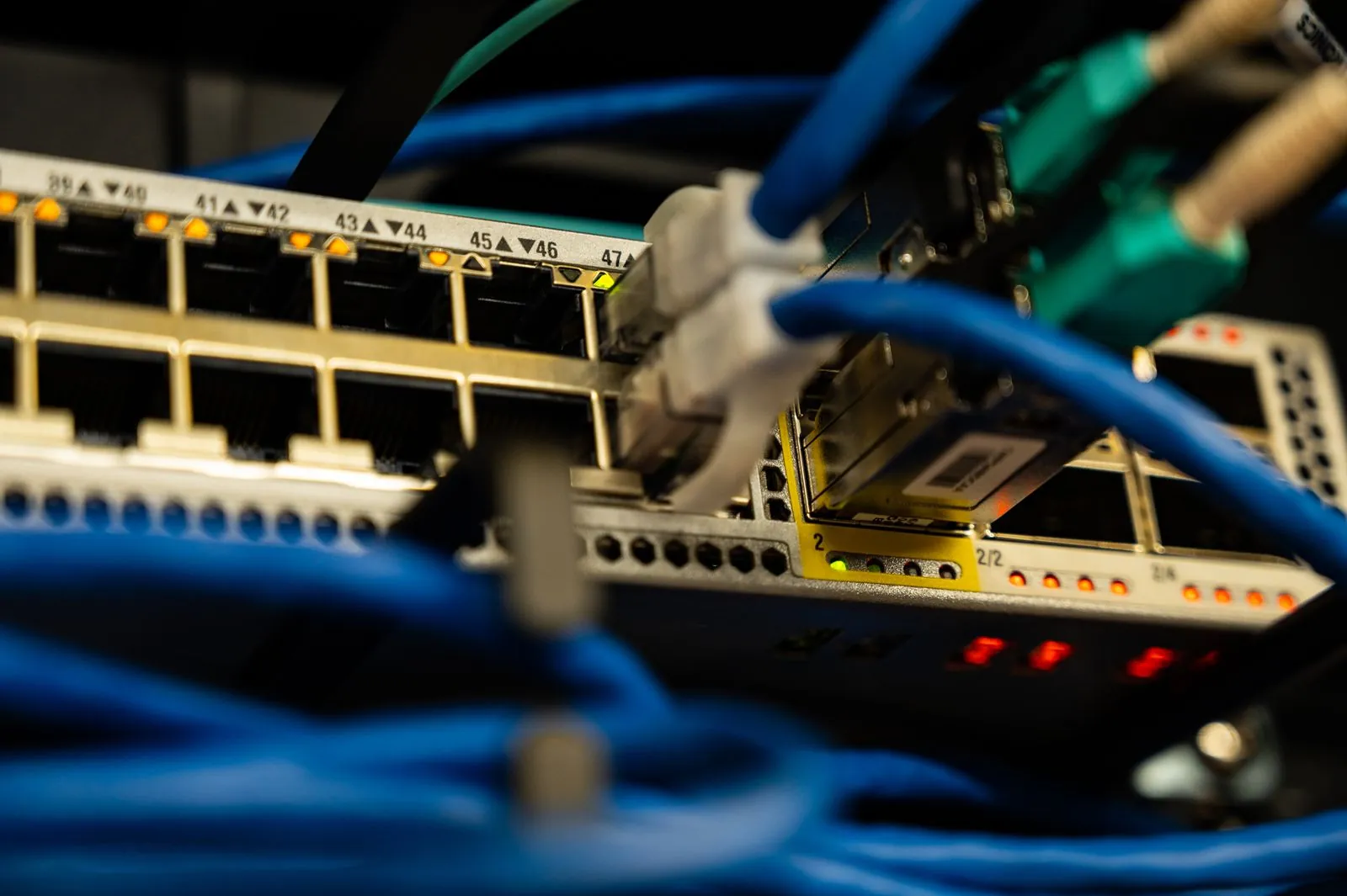 Cables de red azules y módulos SFP conectados a un switch dentro de un rack