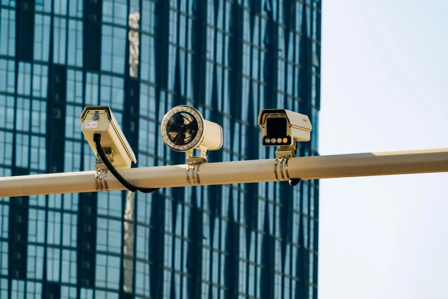 Cámaras de videovigilancia montadas en un poste frente a un edificio de cristal