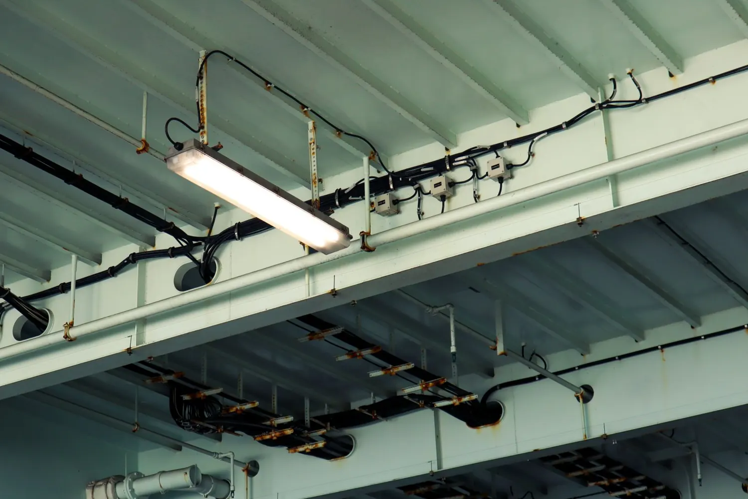 Canalización y cableado corriendo bajo la estructura del techo de una nave industrial
