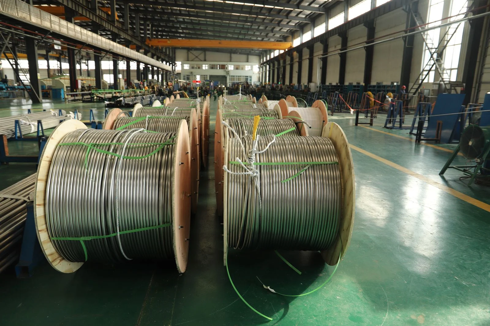 Carretes grandes de cable alineados en el piso de una nave industrial