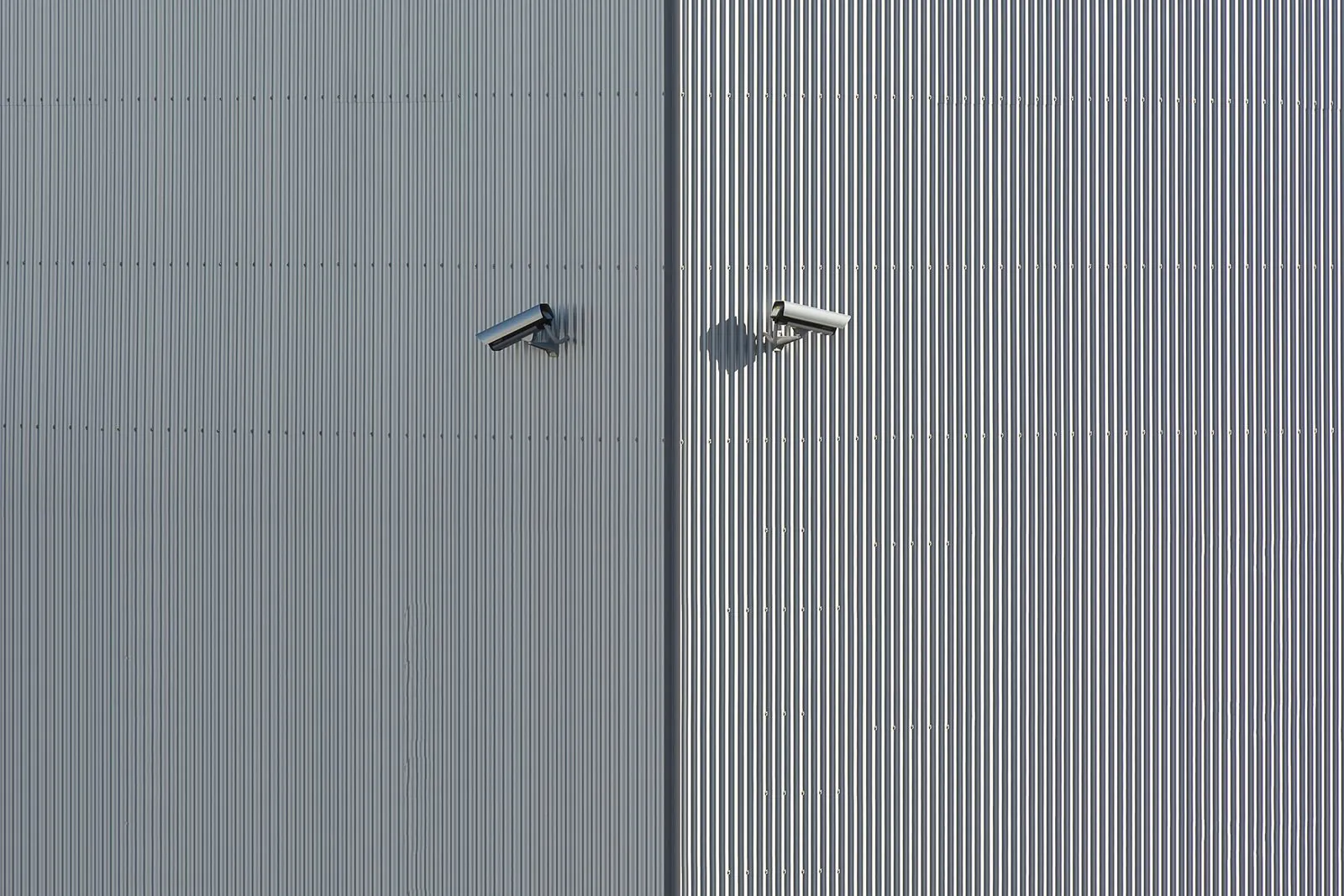 Dos cámaras de vigilancia montadas en un muro metálico exterior