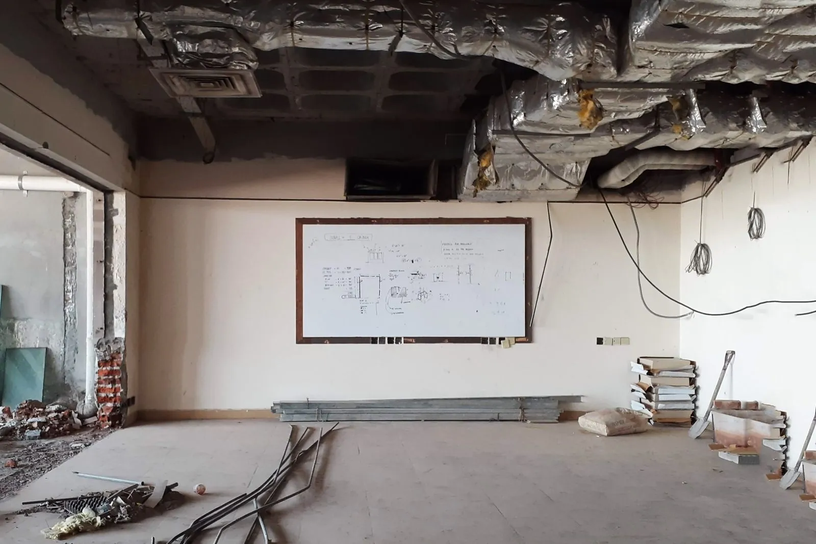 Oficina en obra con el plafón abierto, ductos a la vista y cables colgando del techo