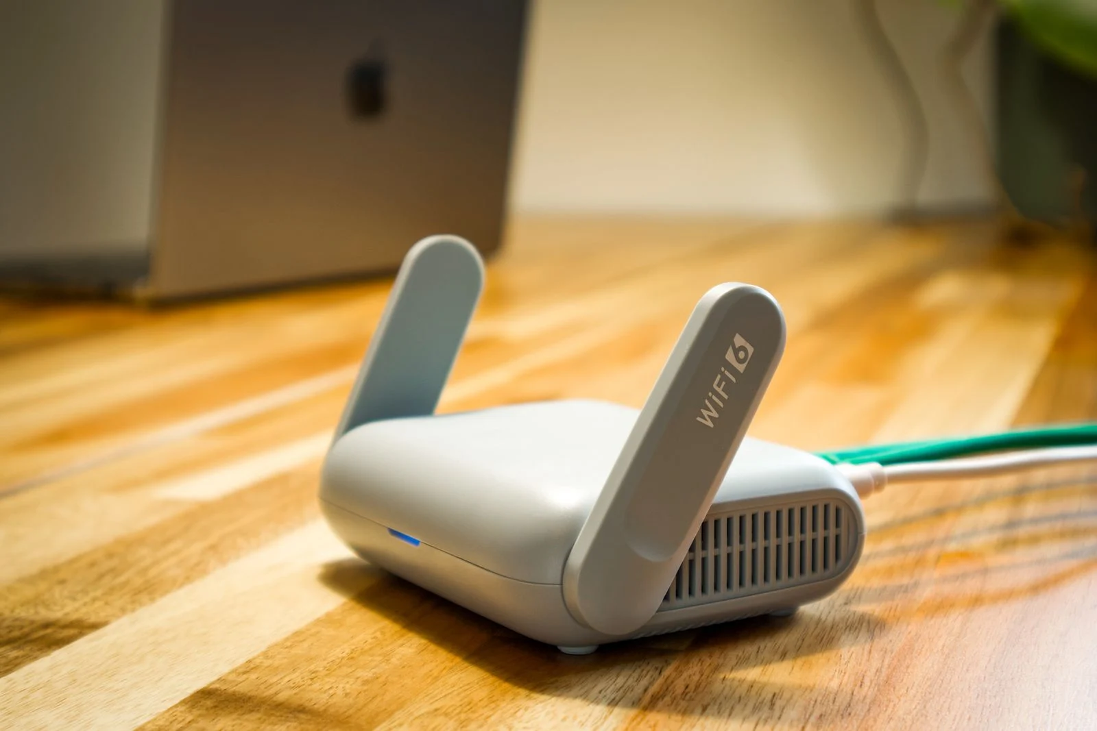 Punto de acceso wifi con antenas y un cable de red conectado en la parte trasera