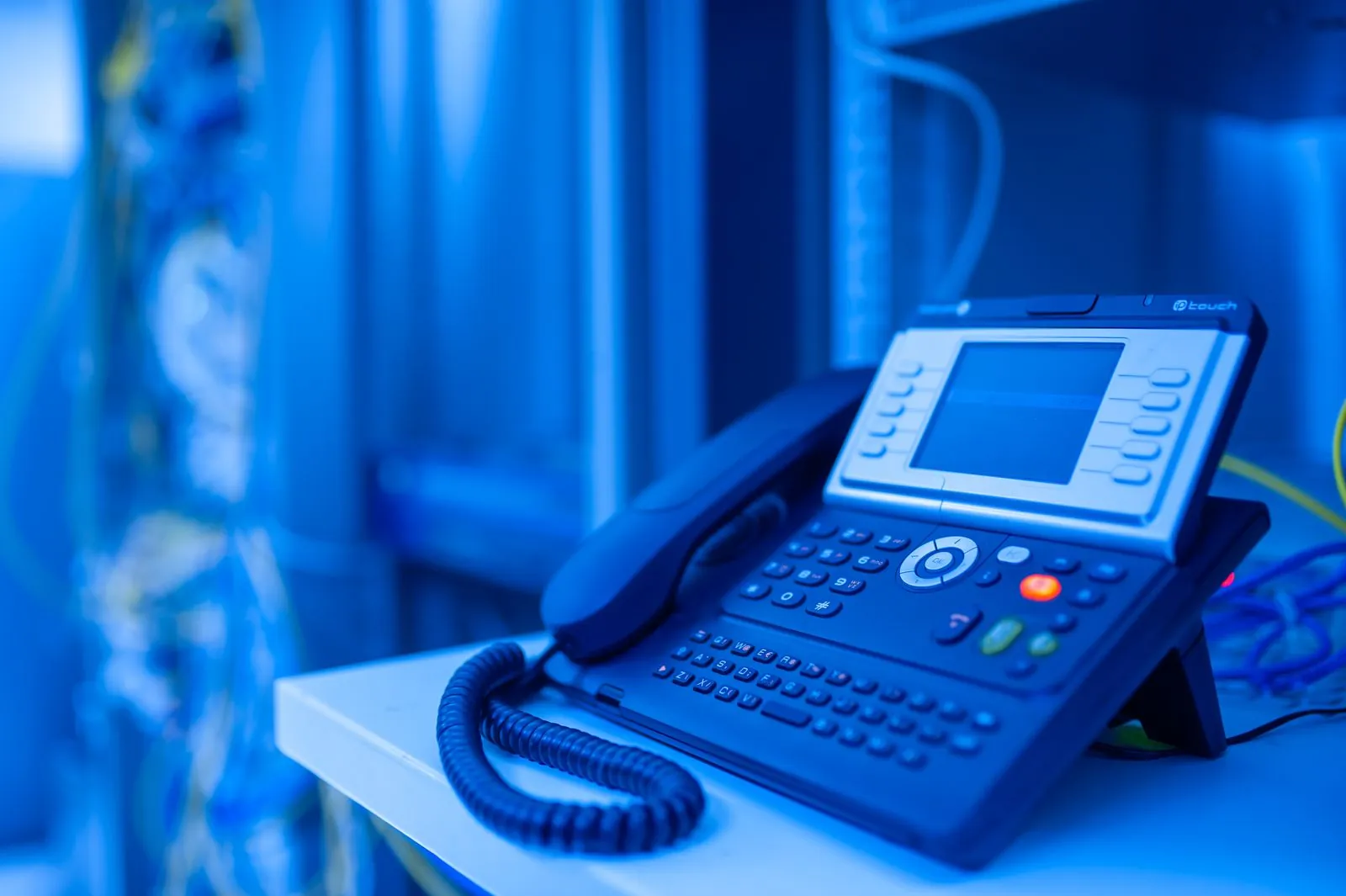 Teléfono IP de escritorio con pantalla sobre un mueble de oficina