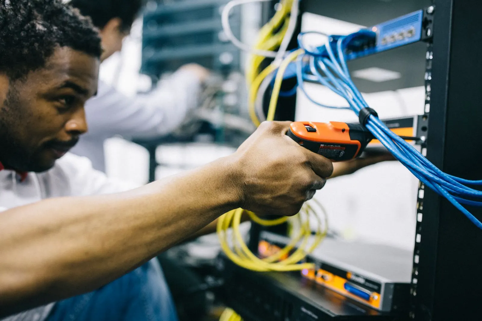 Técnico instalador conectando cables de red azules en un rack de comunicaciones